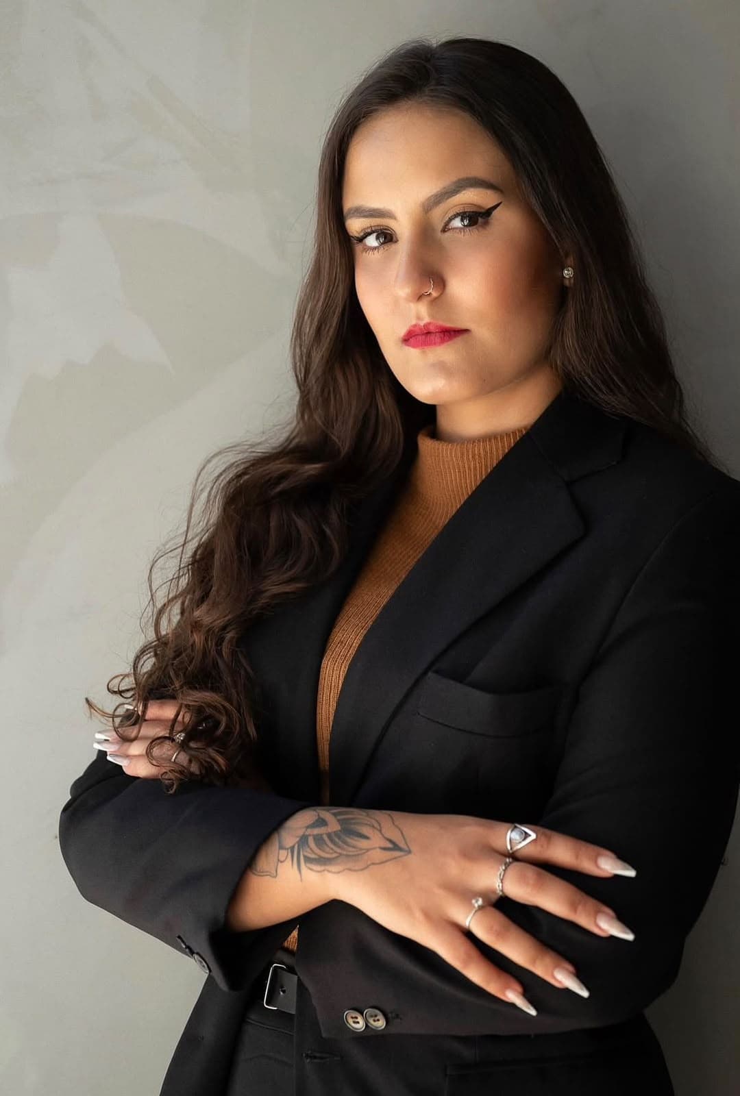 Retrato da advogada Júlia Mendonça, de blazer preto e braços cruzados